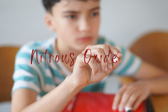 NITROUS OXIDE. Drug alert for teenagers. Preteen boy writing the text on the screen with a red marker