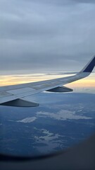 Golden Hour Flight: Airplane Wing Soaring Above Intricate Waterways and Cloudy Sky
