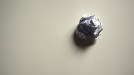 Single crumpled white paper ball on light gray or white background. Concept of mistake, failure, waste, finished work, searching for an idea. Problem, stress, creativity. Ample copy space. Top view.