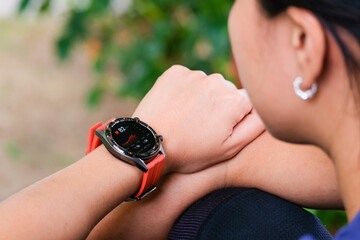 Close-up of a young woman wearing a smartwatch to monitor her heart rate and fitness activity while exercising outdoors, modern wearable technology and healthcare and fitness concept.