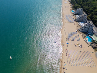 Aerial view of Albena beach in Bulgaria with turquoise sea, sandy shoreline, sun loungers and seaside hotels. Summer resort landscape from drone perspective, travel and tourism concept