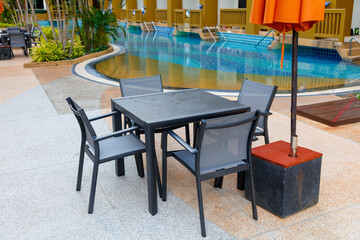 A table and four chairs are set up in front of a pool
