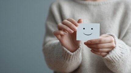 hands holding cute paper smiley face with copy space on grey background