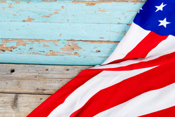 Red and white stripes with stars on usa flag over blue wooden table with copy space