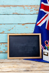 Blank writing slate by australian flag and desk organizer against old wooden wall with copy space © wavebreak3
