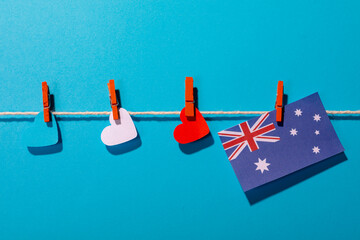 Australia flag with heart shaped papers on clothesline over blue background with copy space