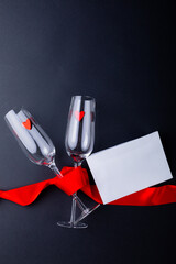 Empty champagne flutes tied with red ribbon by envelope isolated on gray background, copy space