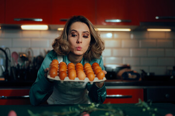 Surprised Woman Holding a Carton of Eggs in the Kitchen. Funny housewife using fresh ingredients for a recipe 
  