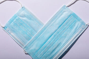 Close-up of protective face masks arranged in heart shape over white background, copy space