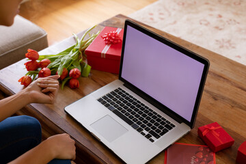 Young woman on valentine's video call through laptop with blank screen showing copy space