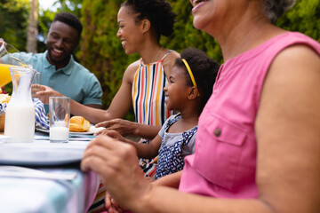 Smiling african american family enjoying brunch at backyard garden