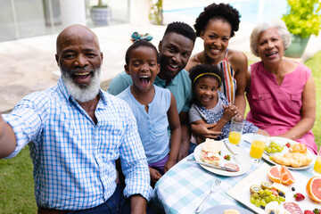Portrait of cheerful african american three generational family taking selfie at brunch