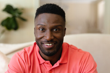 Portrait of african american man smiling while sitting on couch at home