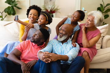 African american three generation family taking a selfie sitting together on the couch at home