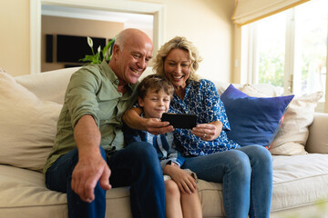 Caucasian grandparents and grandson using digital tablet while sitting on the couch at home