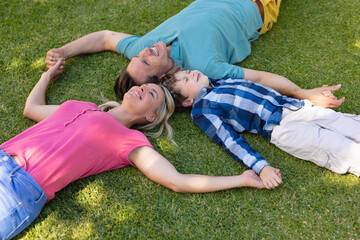 High angle view of caucasian family holding hands and lying together in the garden