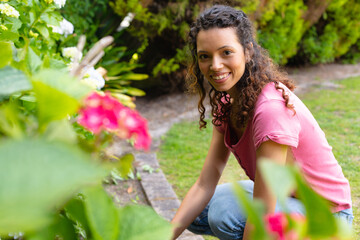 Portrait of smiling young woman with curly hair gardening in backyard