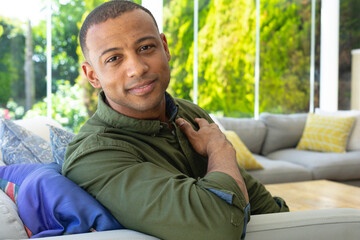 Portrait of young african american man while sitting on sofa at home