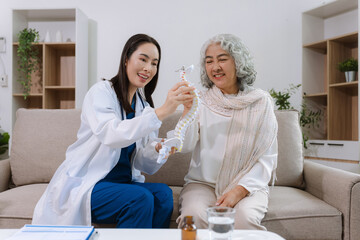 Doctor explains spine surgery using anatomical model, explaining symptoms and treatment to patients.