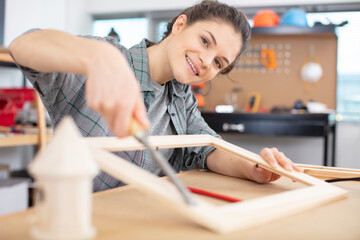 female carpenter measuring wood in workshop