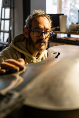 Luthier Inspects a Finely Crafted Carbon Fiber Cello in Warm Workshop Light