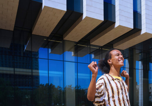 Cheerful person expressing success outdoors near modern glass building