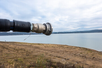 View of a fire hydrant hose ready for use at a lake with low water levels