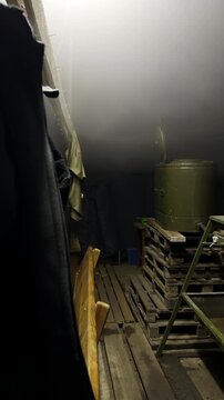 Old pallets and wooden boards with large metal tank in semi-dark blindage. Equipment and funk-hole building supplies prepared in bunker vertical shot