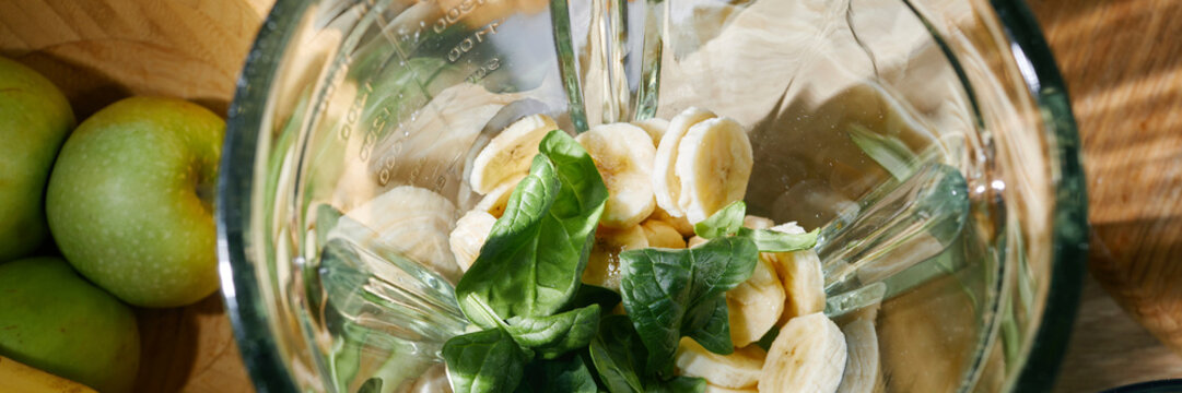 Overhead view of bananas and spinach in a blender for a smoothie preparation
