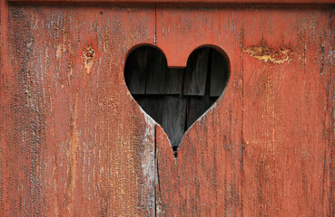 Carved heart shape in weathered red painted wooden board in Switzerland