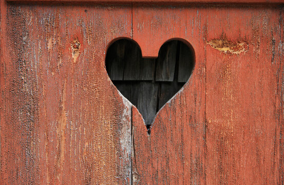 Carved heart shape in weathered red painted wooden board in Switzerland