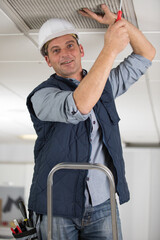 construction worker repairing ceiling with air duct