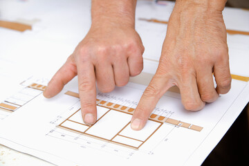 Hands of carpenters analyzing blueprint for woodworking project