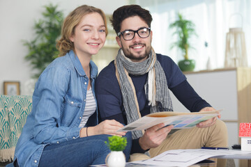 couple sitting on sofa looking at paint charts