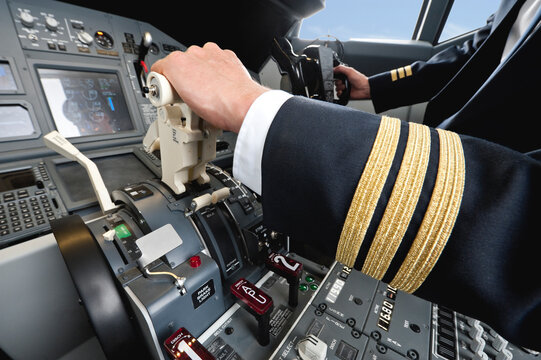 Pilot operating airplane cockpit controls wearing uniform