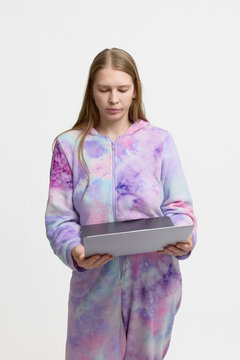 Young woman in colorful casual homewear holding a tablet and looking down at the screen, isolated on white background. Concept of remote work, online learning, digital lifestyle