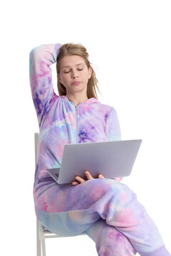 Young woman sitting on a chair and using a laptop, isolated on white background. Casual home outfit and relaxed pose convey remote work, freelancing, online learning, digital lifestyle
