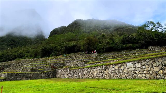 Morning foggy sunrise Inca trail Machu Picchu stonework tourist circuit landscape sunny fog clouds Peruvian Andes Peru Per&uacute; historic Inca Sanctuary Temple rainy season lush green jungle pan left