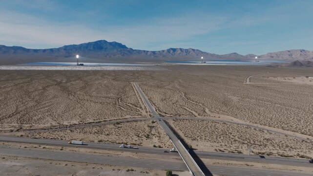 Aerial drone footage of the Ivanpah Solar Power Facility in the Mojave Desert showing solar towers, heliostats, and nearby highway generating large scale renewable solar energy in California.