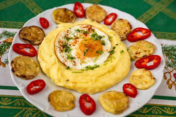 Mashed potato with fried egg, zuchini and red pepper on white plate.
