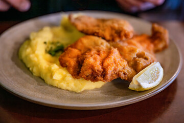 Fried schnitzel with mashed potato, lemon on plate, closeup.