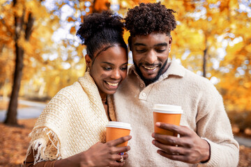 African American Couple Walking with Coffee in Autumn Park
