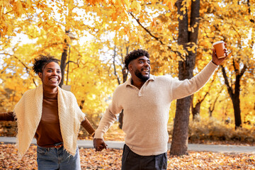 African American Couple Walking with Coffee in Autumn Park