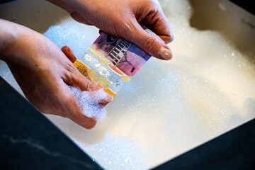 Hands Washing a Banknote in Soapy Sink &mdash; Money Laundering Concept