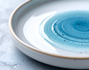 Shallow, white ceramic plate with blue swirl glaze detail