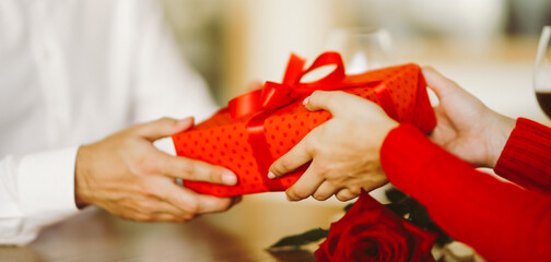 Man gives to his woman a gift box with red ribbon. Valentine's Day, holiday and surprise concept.