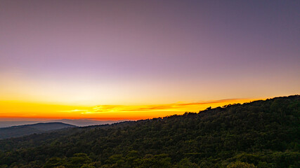 A breathtaking sunset over layered mountain ranges, with warm golden light fading into a deep blue sky, creating a serene and expansive natural landscape ideal for travel and nature themes. © Narong Niemhom