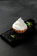 A sand basket with protein cream stands on a black wooden board on a gray background