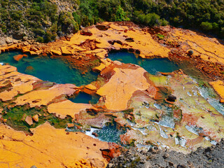 Aerial view of vibrant thermal mineral pools in a unique, colorful geological landscape, showcasing...