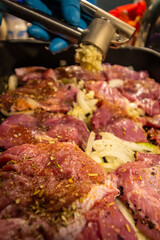 squeezing garlic onto meat sprinkled with seasonings and spices. close-up. cooking.